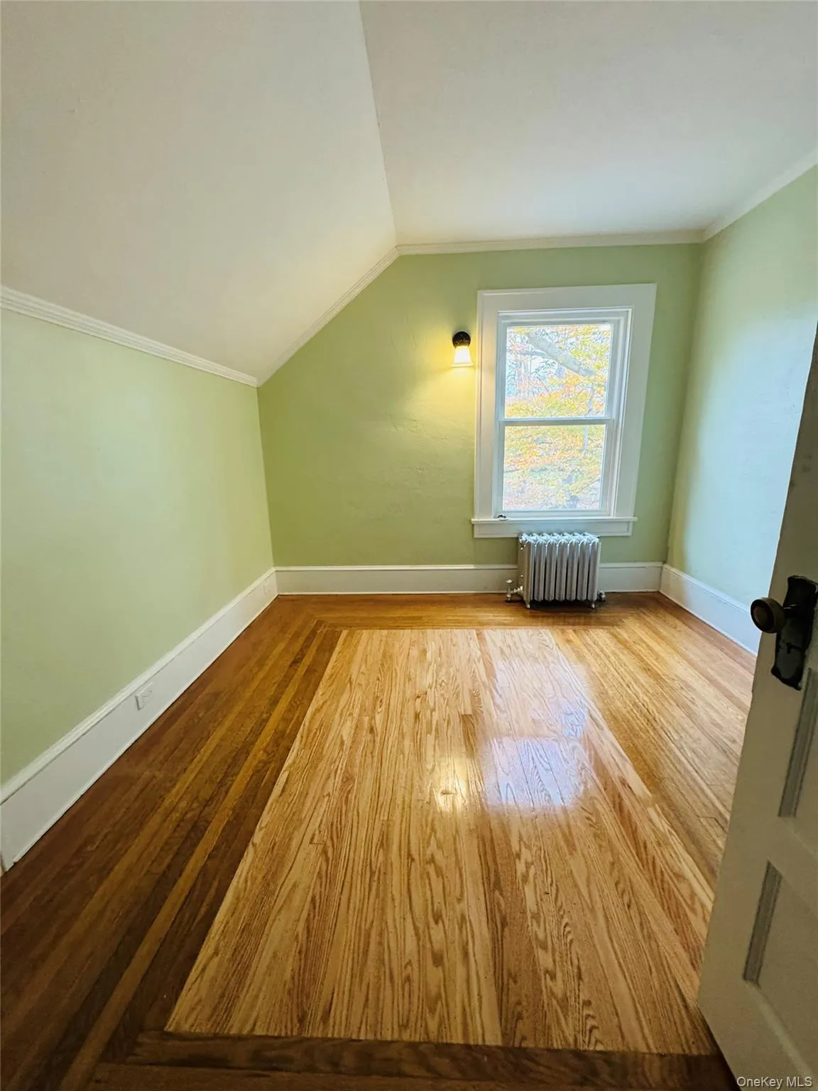 Additional living space with hardwood / wood-style floors, radiator heating unit, and vaulted ceiling Additional living space with hardwood / wood-style floors, radiator heating unit, and vaulted ceiling