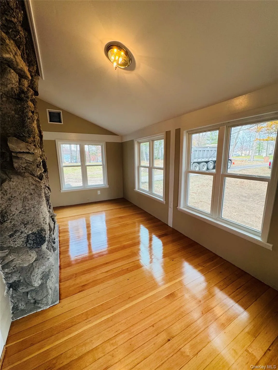 Unfurnished living room featuring light wood-style floors and lofted ceiling Unfurnished living room featuring light wood-style floors and lofted ceiling
