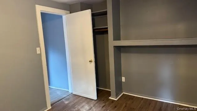 Unfurnished bedroom featuring dark wood finished floors and a closet Unfurnished bedroom featuring dark wood finished floors and a closet