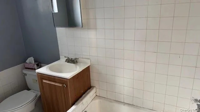 Bathroom featuring tile walls, a bathtub, and vanity Bathroom featuring tile walls, a bathtub, and vanity