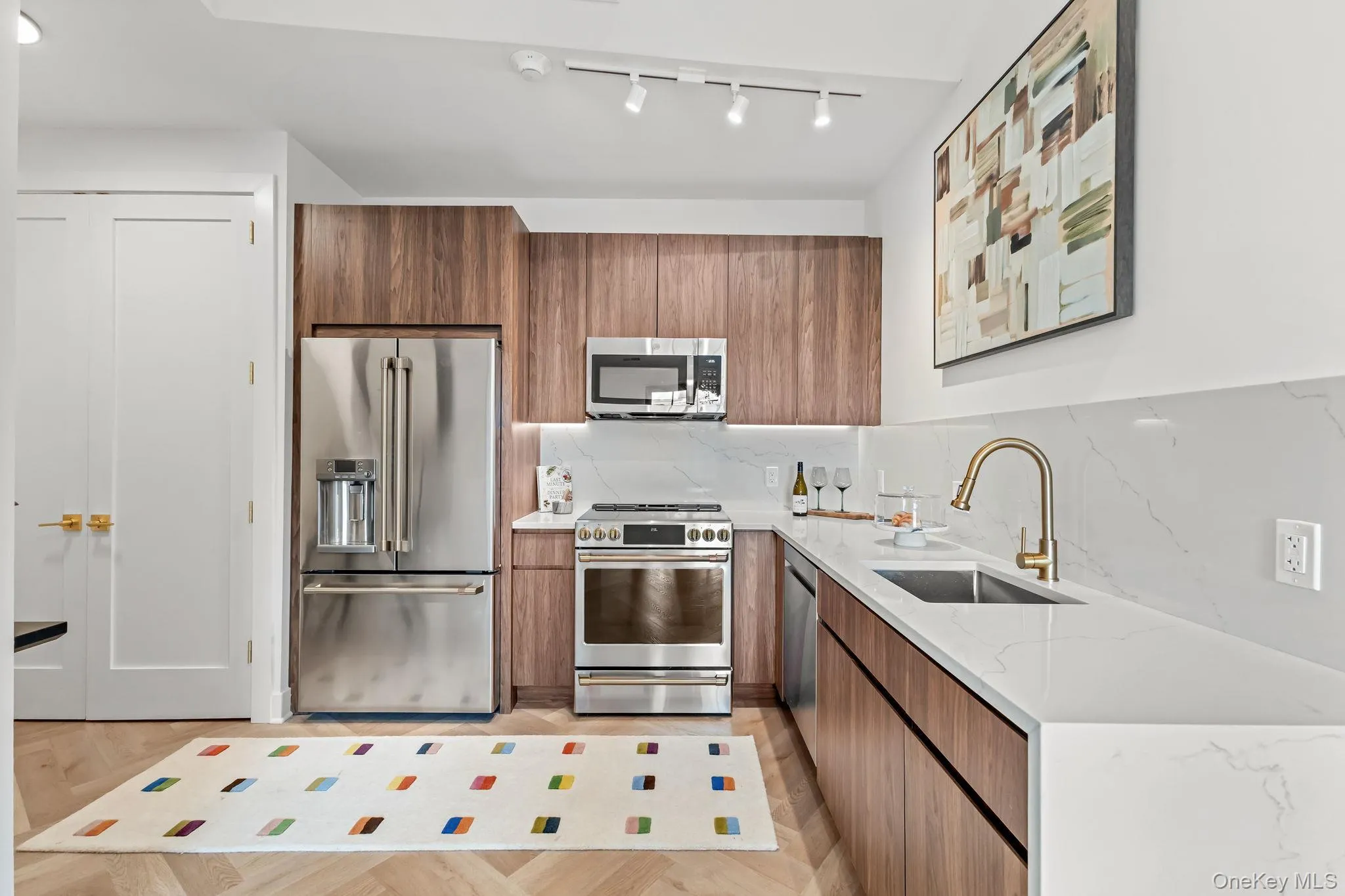 Kitchen with brown cabinetry, light stone countertops, appliances with stainless steel finishes, tasteful backsplash, and modern cabinets Kitchen with brown cabinetry, light stone countertops, appliances with stainless steel finishes, tasteful backsplash, and modern cabinets