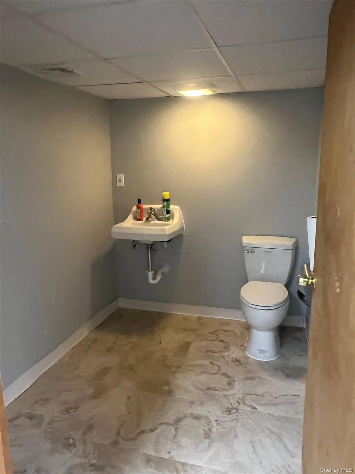 Bathroom featuring a drop ceiling and baseboards Bathroom featuring a drop ceiling and baseboards
