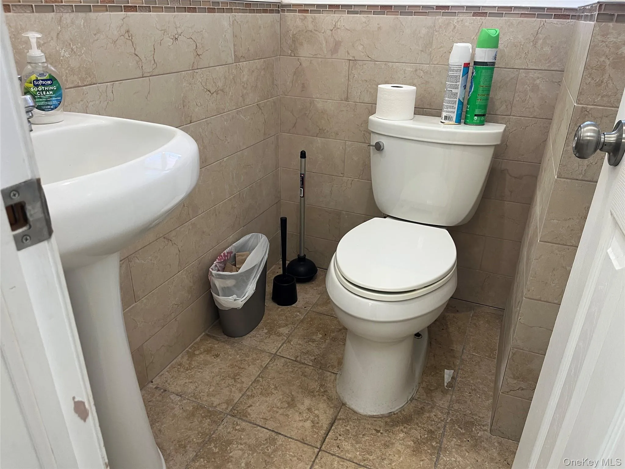 Half bath featuring tile patterned floors and tile walls Half bath featuring tile patterned floors and tile walls