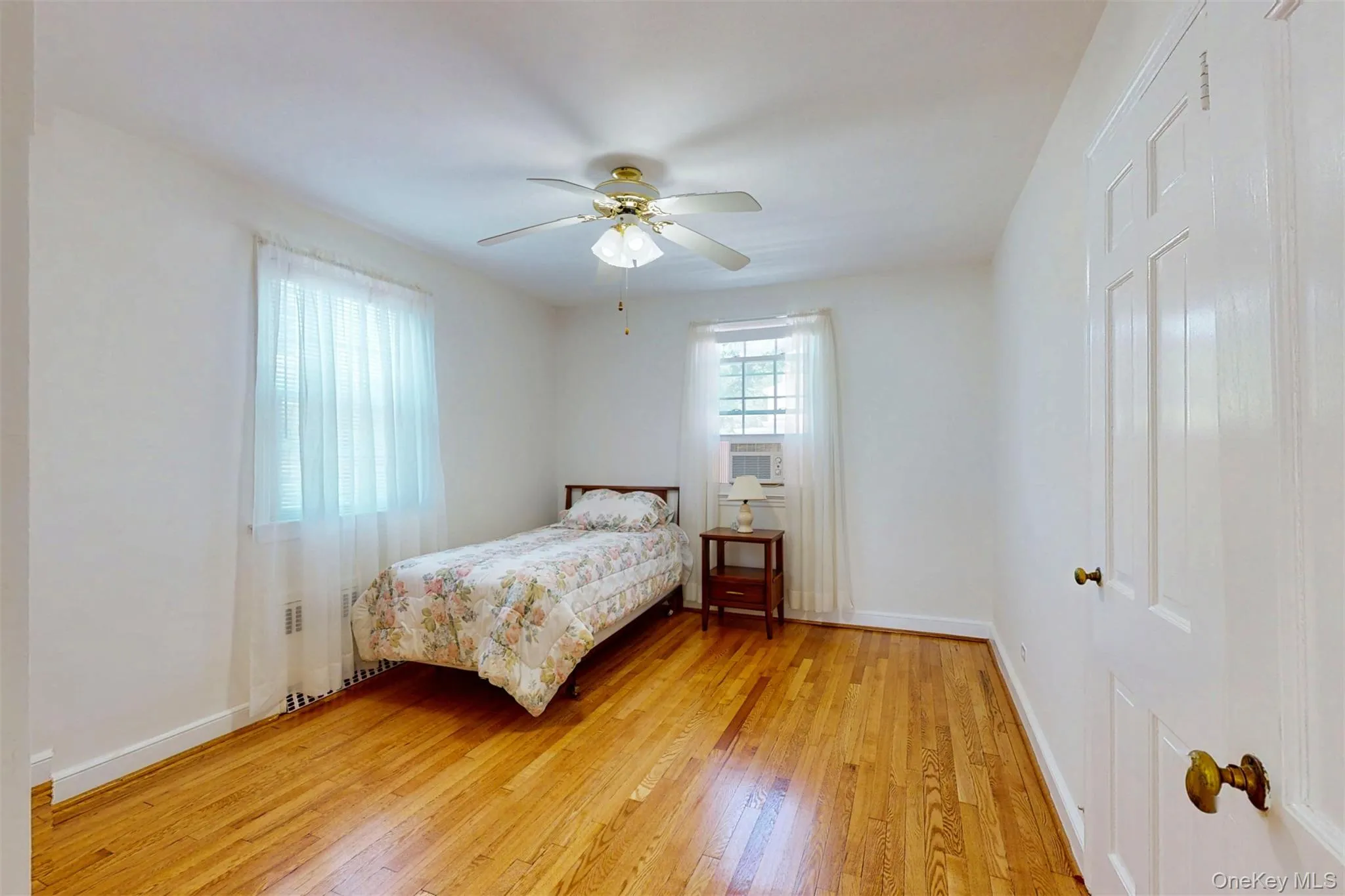 Bedroom featuring hardwood floors and a ceiling fan/light, recessed radiator, large closet Bedroom featuring hardwood floors and a ceiling fan/light, recessed radiator, large closet