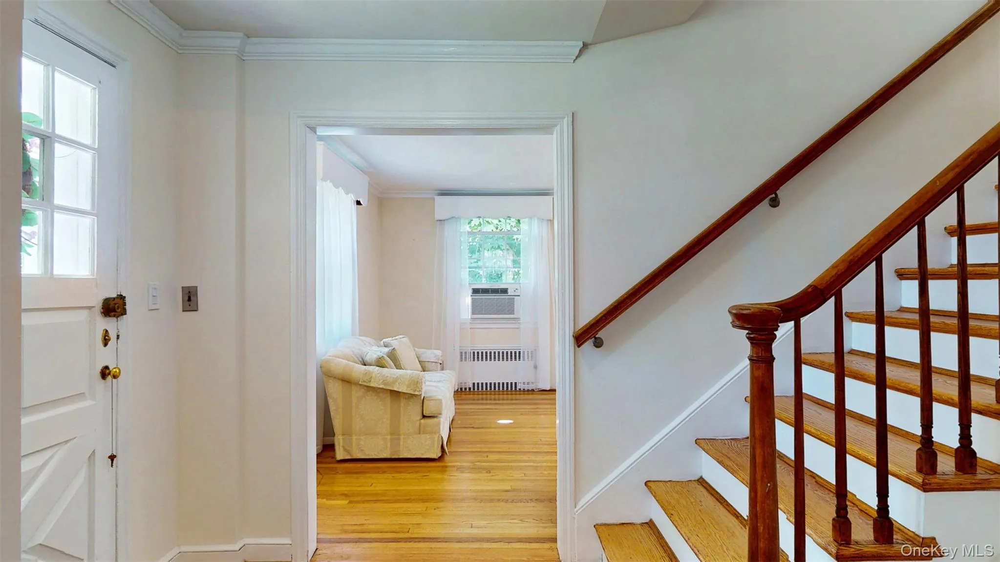 Entrance foyer featuring recessed radiator heating unit, gleaming hardwood floors, crown molding, and double deep coat closet Entrance foyer featuring recessed radiator heating unit, gleaming hardwood floors, crown molding, and double deep coat closet