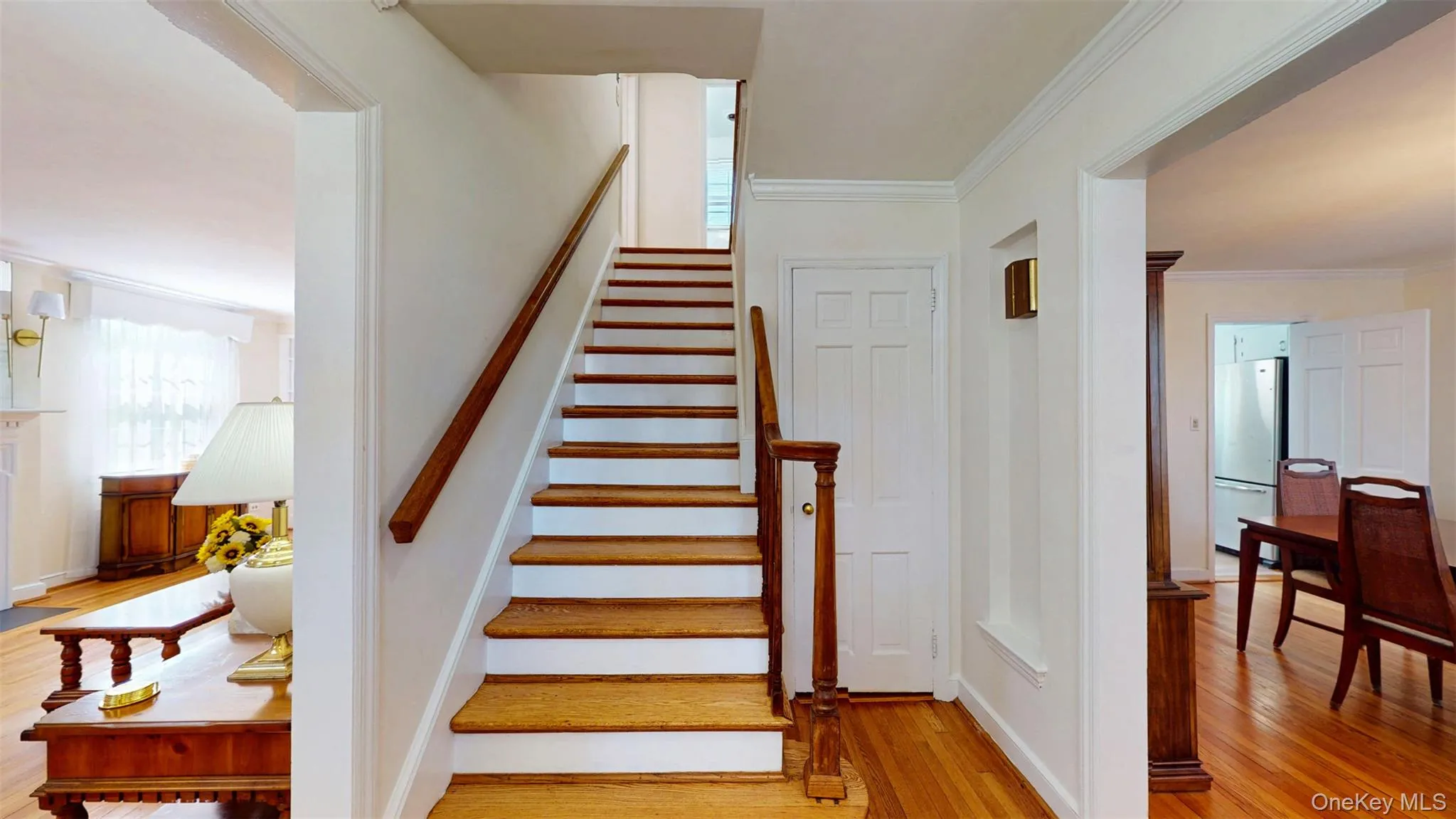 Staircase featuring wood finished floors and crown molding Staircase featuring wood finished floors and crown molding