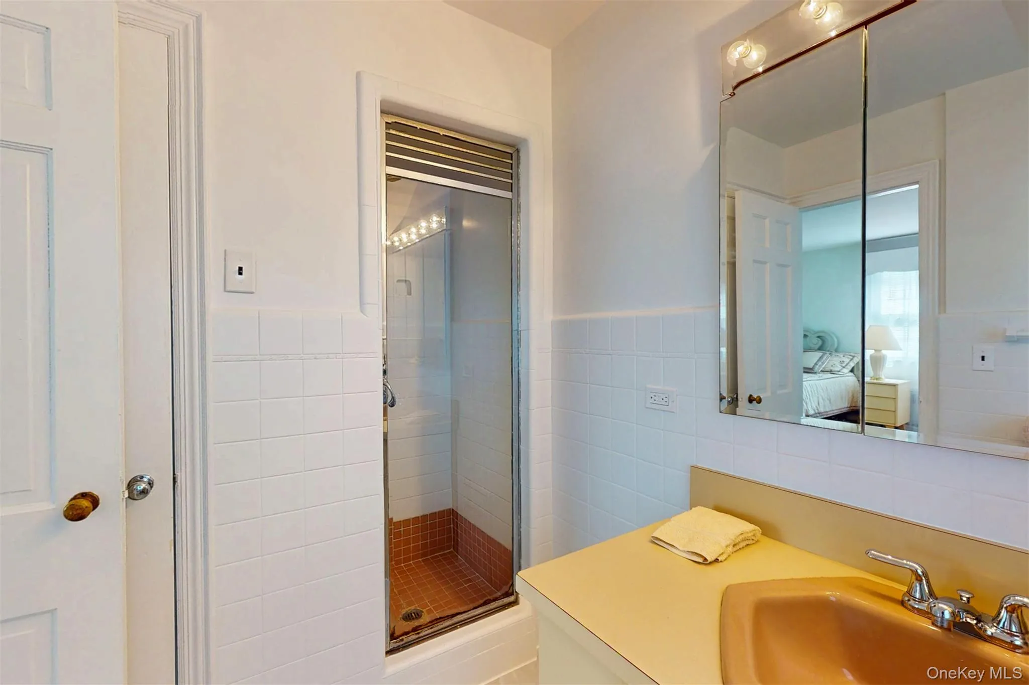 Ensuite bathroom featuring tile walls, a stall shower, vanity, and wainscoting Ensuite bathroom featuring tile walls, a stall shower, vanity, and wainscoting