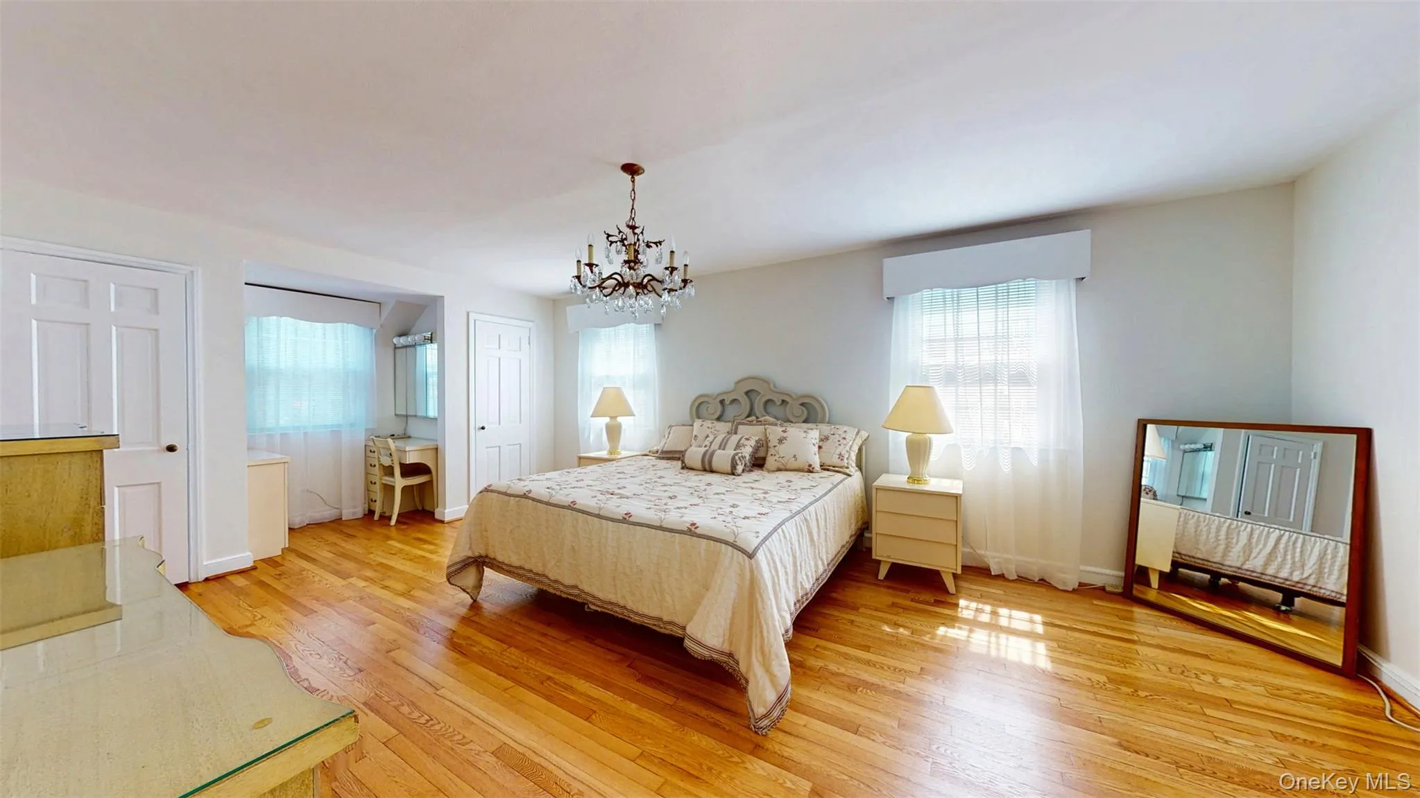 Huge Primary Bedroom featuring a chandelier and hardwood flooring with 3 closets and dressing/makeup area with ensuite Huge Primary Bedroom featuring a chandelier and hardwood flooring with 3 closets and dressing/makeup area with ensuite