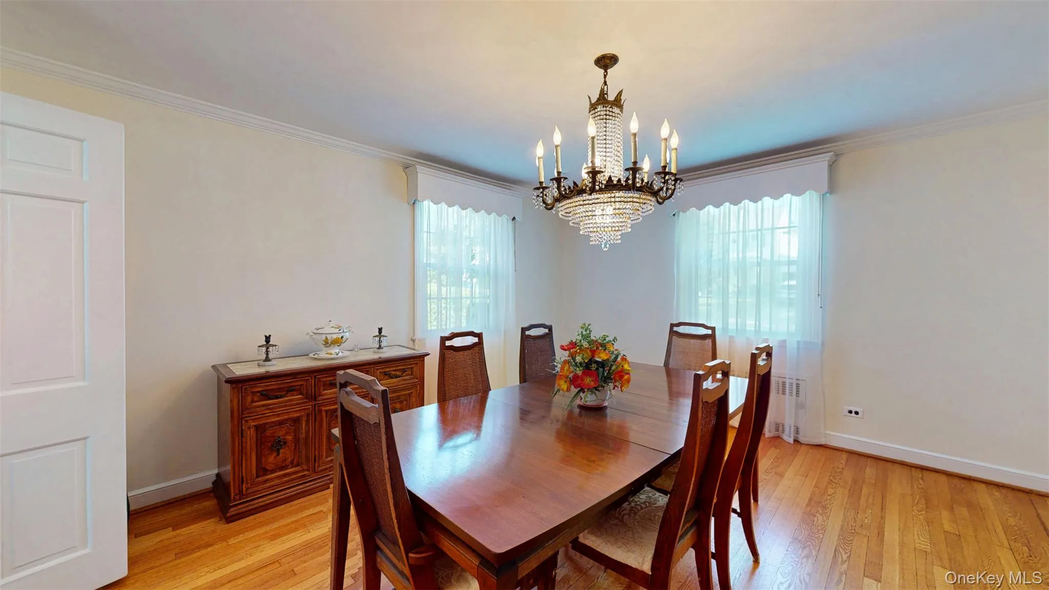 Dining space featuring a chandelier, plenty of natural light, light wood-style flooring, crown molding, and radiator heating unit Dining space featuring a chandelier, plenty of natural light, light wood-style flooring, crown molding, and radiator heating unit