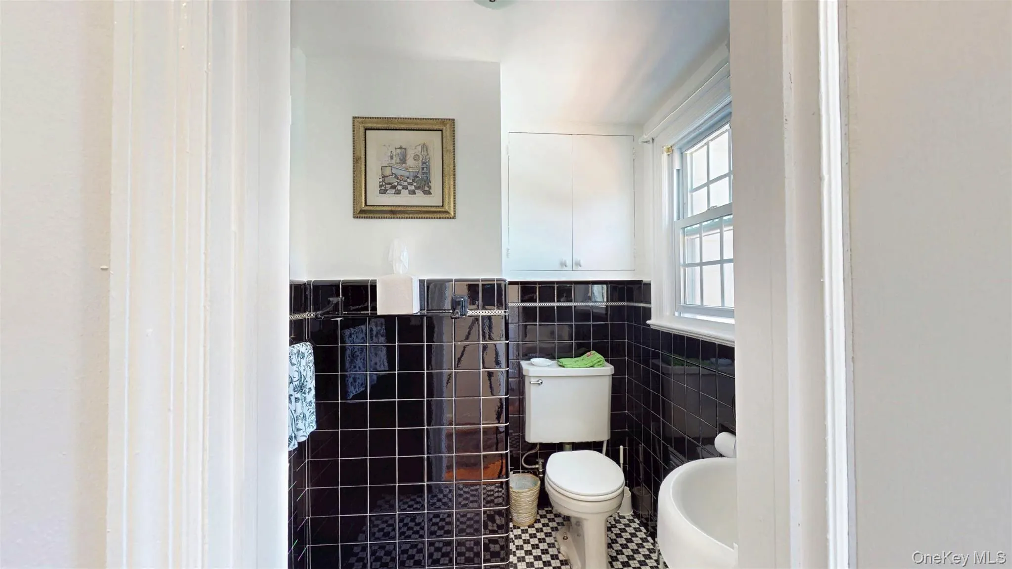 Spacious Half Bathroom with tile walls, black and white checkered tile floors Spacious Half Bathroom with tile walls, black and white checkered tile floors
