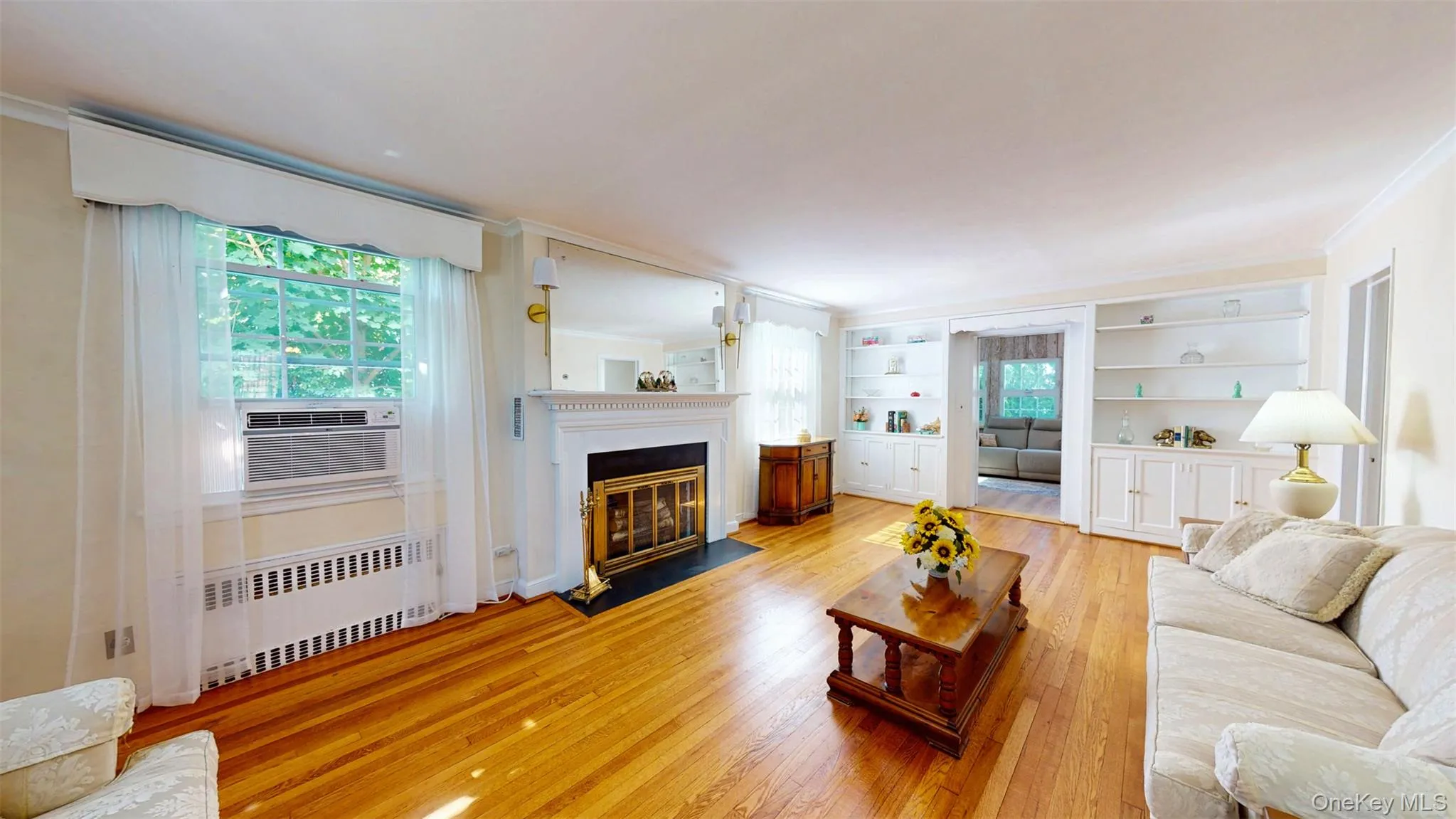 Living room with 2 recessed radiator heating units, hardwood finished floors, crown molding, and a fireplace with black marble hearth Living room with 2 recessed radiator heating units, hardwood finished floors, crown molding, and a fireplace with black marble hearth