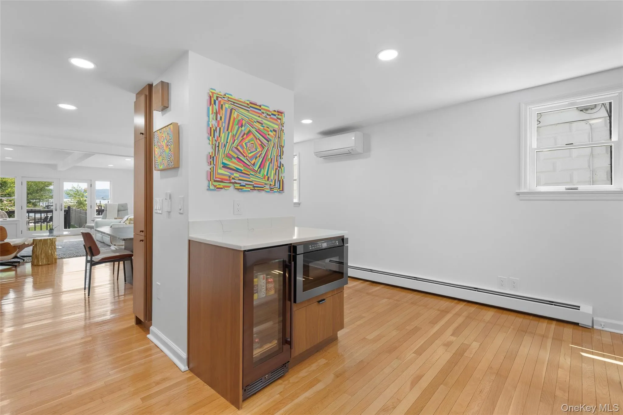 Bar with light wood finished floors, a baseboard heating unit, wine cooler, recessed lighting, and brown cabinets Bar with light wood finished floors, a baseboard heating unit, wine cooler, recessed lighting, and brown cabinets