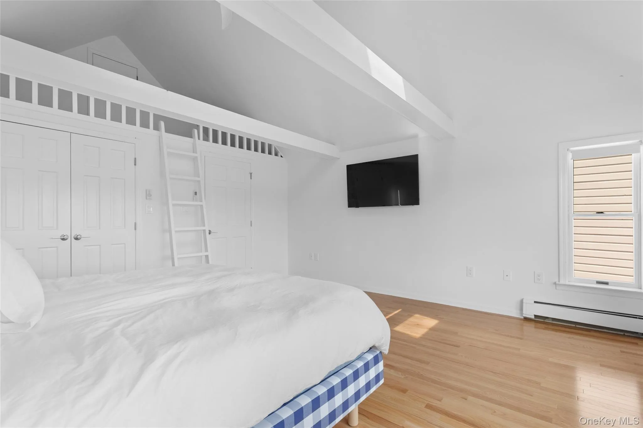 Bedroom featuring wood finished floors, lofted ceiling, and a baseboard heating unit Bedroom featuring wood finished floors, lofted ceiling, and a baseboard heating unit