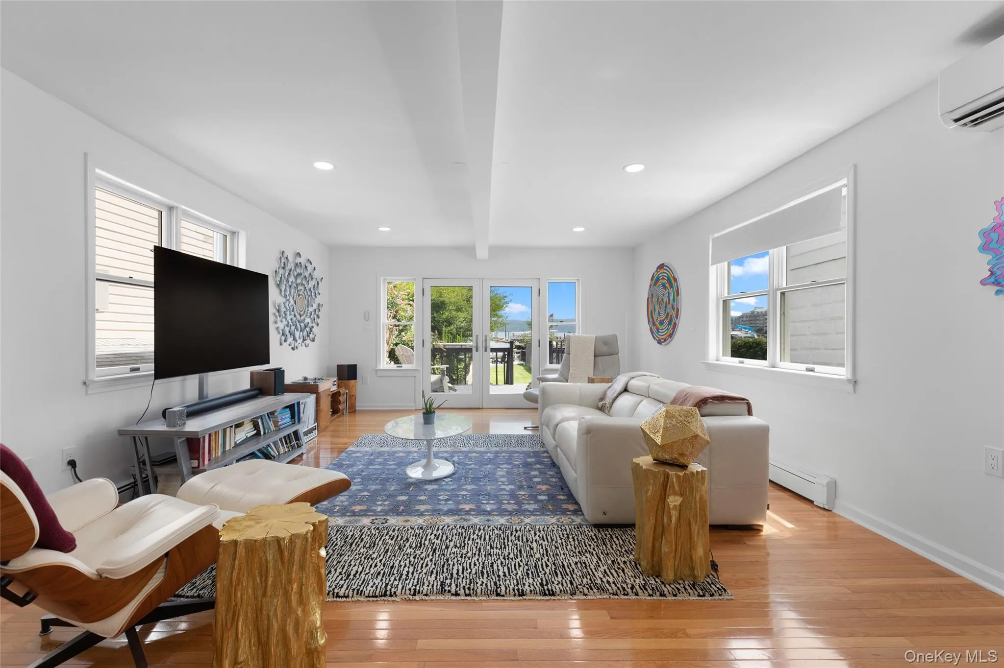 Living area with light wood-type flooring, healthy amount of natural light, a baseboard heating unit, recessed lighting, and beam ceiling Living area with light wood-type flooring, healthy amount of natural light, a baseboard heating unit, recessed lighting, and beam ceiling