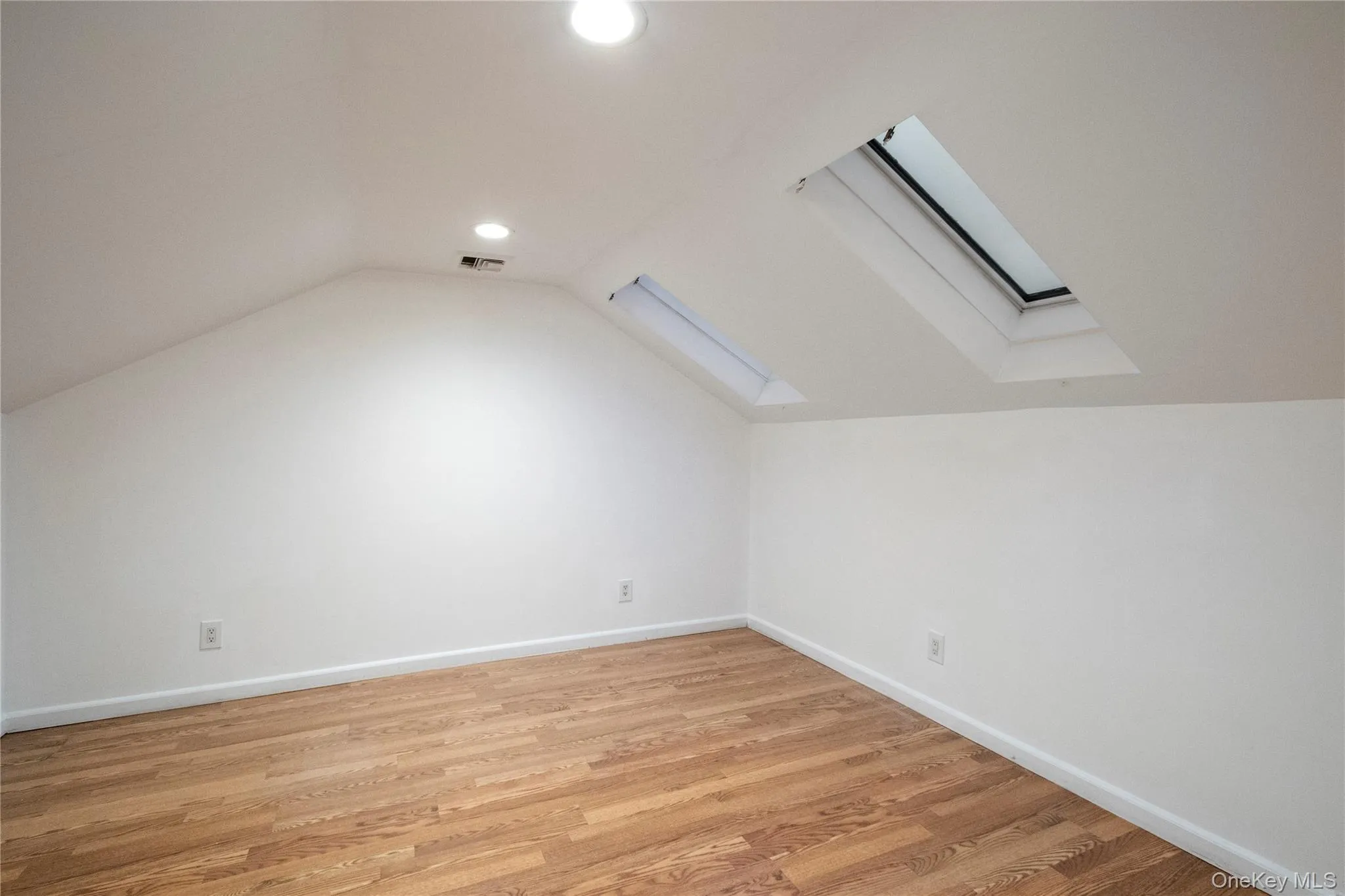Bonus room with vaulted ceiling, a skylight, and light wood-type flooring Bonus room with vaulted ceiling, a skylight, and light wood-type flooring