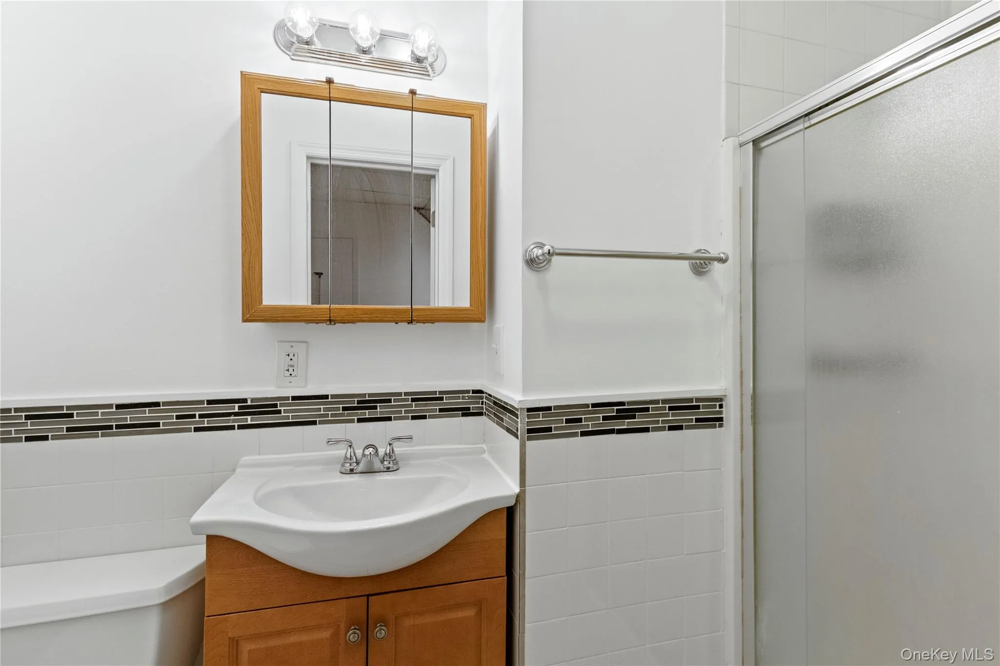 Full bathroom with vanity, a stall shower, and tile walls Full bathroom with vanity, a stall shower, and tile walls