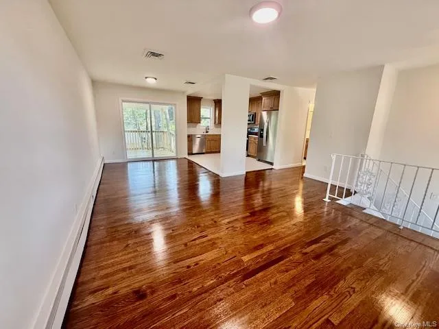 Unfurnished living room with dark wood finished floors and a baseboard radiator Unfurnished living room with dark wood finished floors and a baseboard radiator