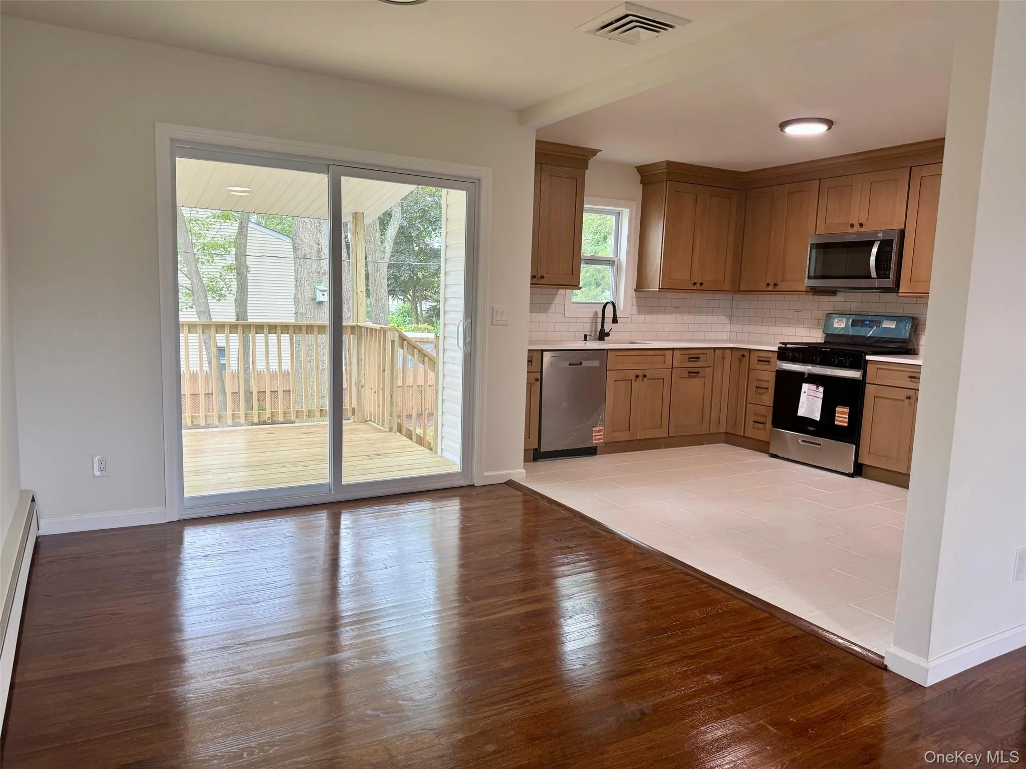 Kitchen with backsplash, appliances with stainless steel finishes, light countertops, light wood-style floors, and a baseboard heating unit Kitchen with backsplash, appliances with stainless steel finishes, light countertops, light wood-style floors, and a baseboard heating unit