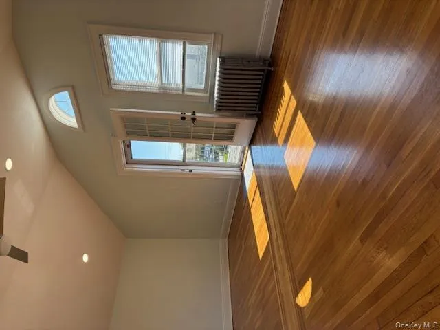 Empty room featuring dark wood-type flooring, radiator, recessed lighting, lofted ceiling, and french doors Empty room featuring dark wood-type flooring, radiator, recessed lighting, lofted ceiling, and french doors