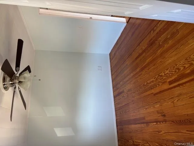 Spare room with ornamental molding, dark wood-type flooring, and a ceiling fan Spare room with ornamental molding, dark wood-type flooring, and a ceiling fan