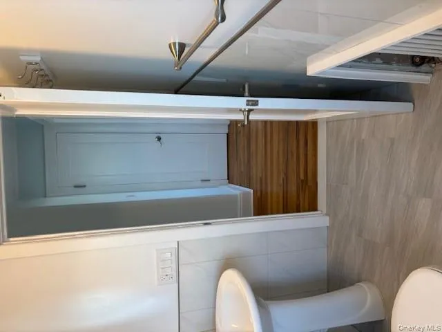 Half bathroom featuring wood finished floors, tile walls, and a wainscoted wall Half bathroom featuring wood finished floors, tile walls, and a wainscoted wall