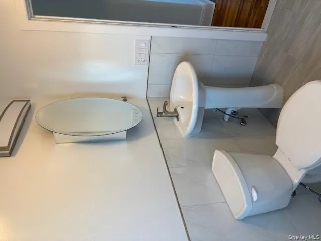 Bathroom featuring wood finished floors, tile walls, and wainscoting Bathroom featuring wood finished floors, tile walls, and wainscoting