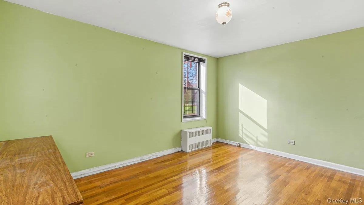 Spare room featuring hardwood / wood-style flooring and radiator heating unit Spare room featuring hardwood / wood-style flooring and radiator heating unit