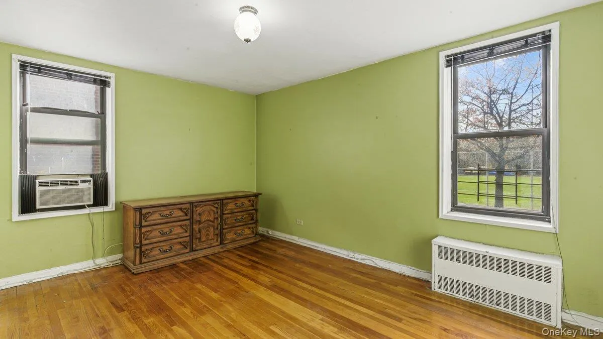 Empty room with radiator, wood finished floors, and cooling unit Empty room with radiator, wood finished floors, and cooling unit