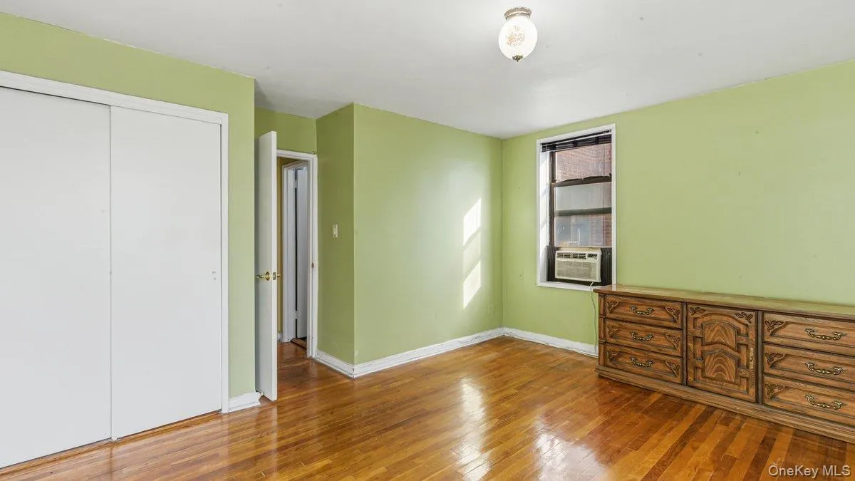 Unfurnished bedroom featuring a closet, wood finished floors, and cooling unit Unfurnished bedroom featuring a closet, wood finished floors, and cooling unit