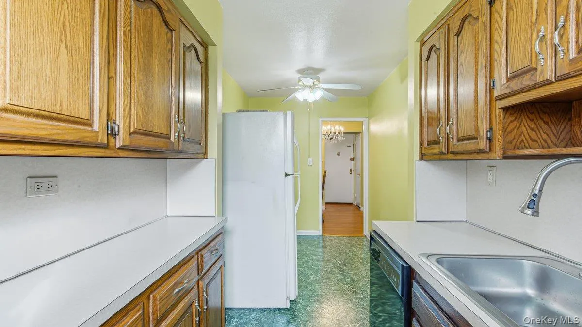 Kitchen with freestanding refrigerator, brown cabinets, light countertops, and dishwasher Kitchen with freestanding refrigerator, brown cabinets, light countertops, and dishwasher