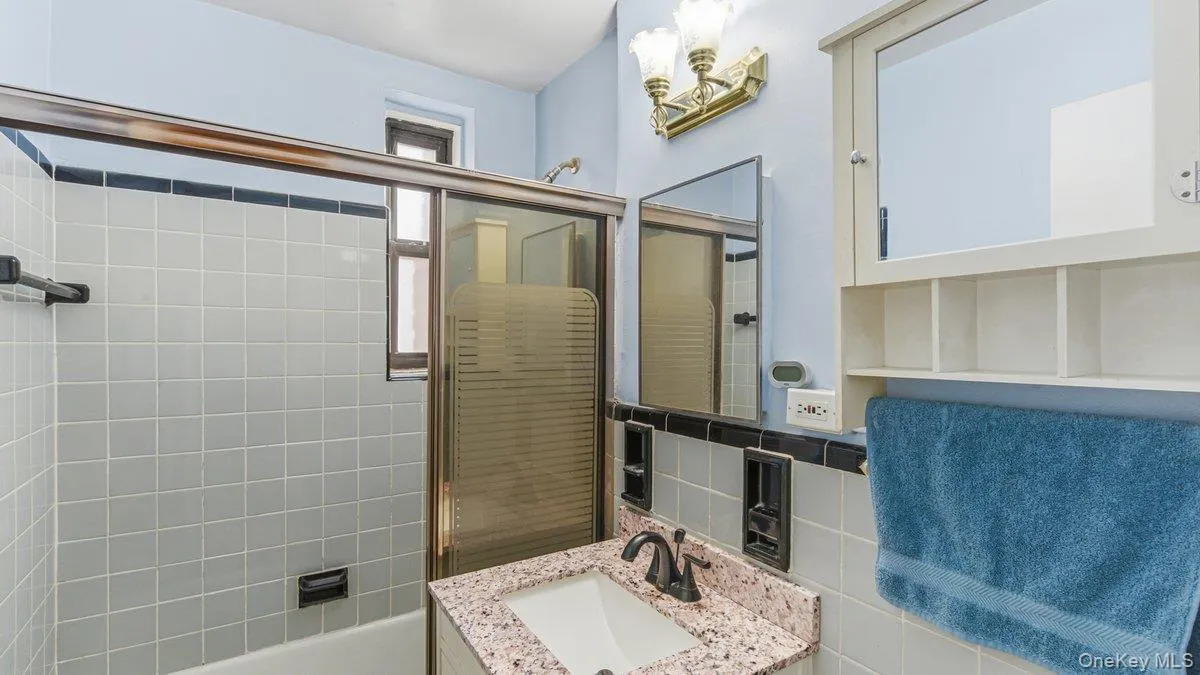 Bathroom with vanity, combined bath / shower with glass door, and tile walls Bathroom with vanity, combined bath / shower with glass door, and tile walls