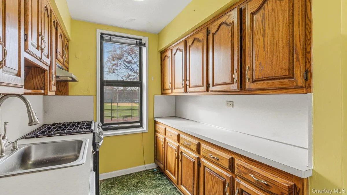 Kitchen featuring brown cabinets, stainless steel gas range, light countertops, and under cabinet range hood Kitchen featuring brown cabinets, stainless steel gas range, light countertops, and under cabinet range hood