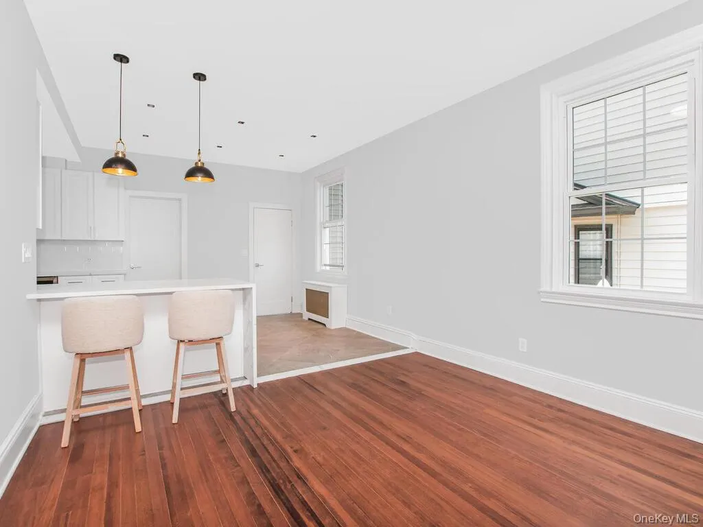 Kitchen featuring a breakfast bar area, white cabinetry, dark wood-style floors, light countertops, and hanging light fixtures Kitchen featuring a breakfast bar area, white cabinetry, dark wood-style floors, light countertops, and hanging light fixtures