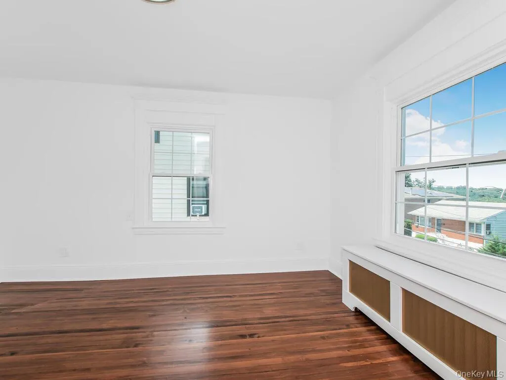 Spare room with radiator heating unit and dark wood-style flooring Spare room with radiator heating unit and dark wood-style flooring