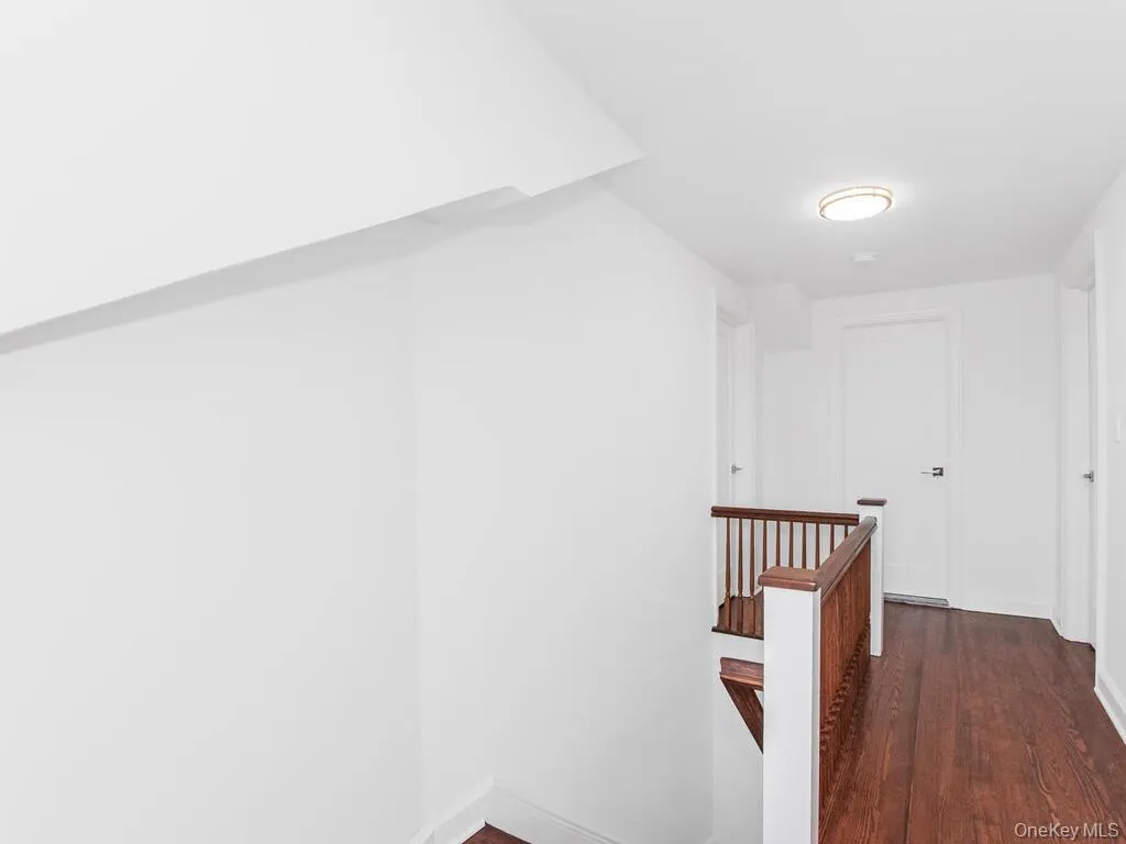 Hall featuring an upstairs landing and dark wood-type flooring Hall featuring an upstairs landing and dark wood-type flooring