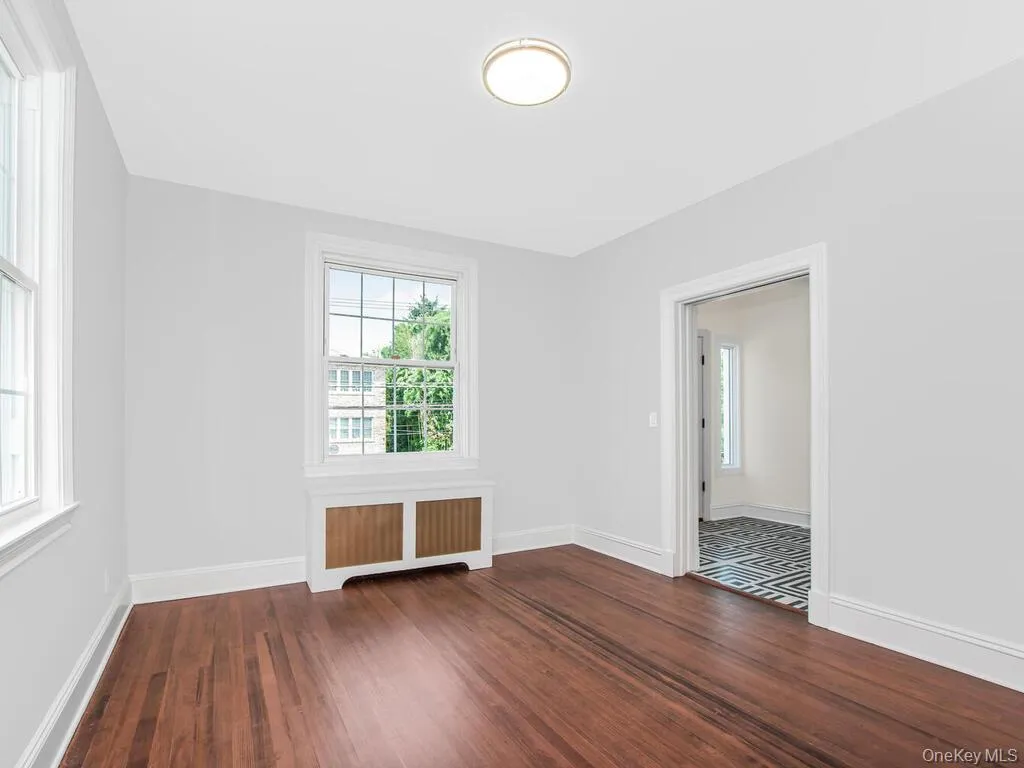 Spare room featuring radiator heating unit and wood finished floors Spare room featuring radiator heating unit and wood finished floors
