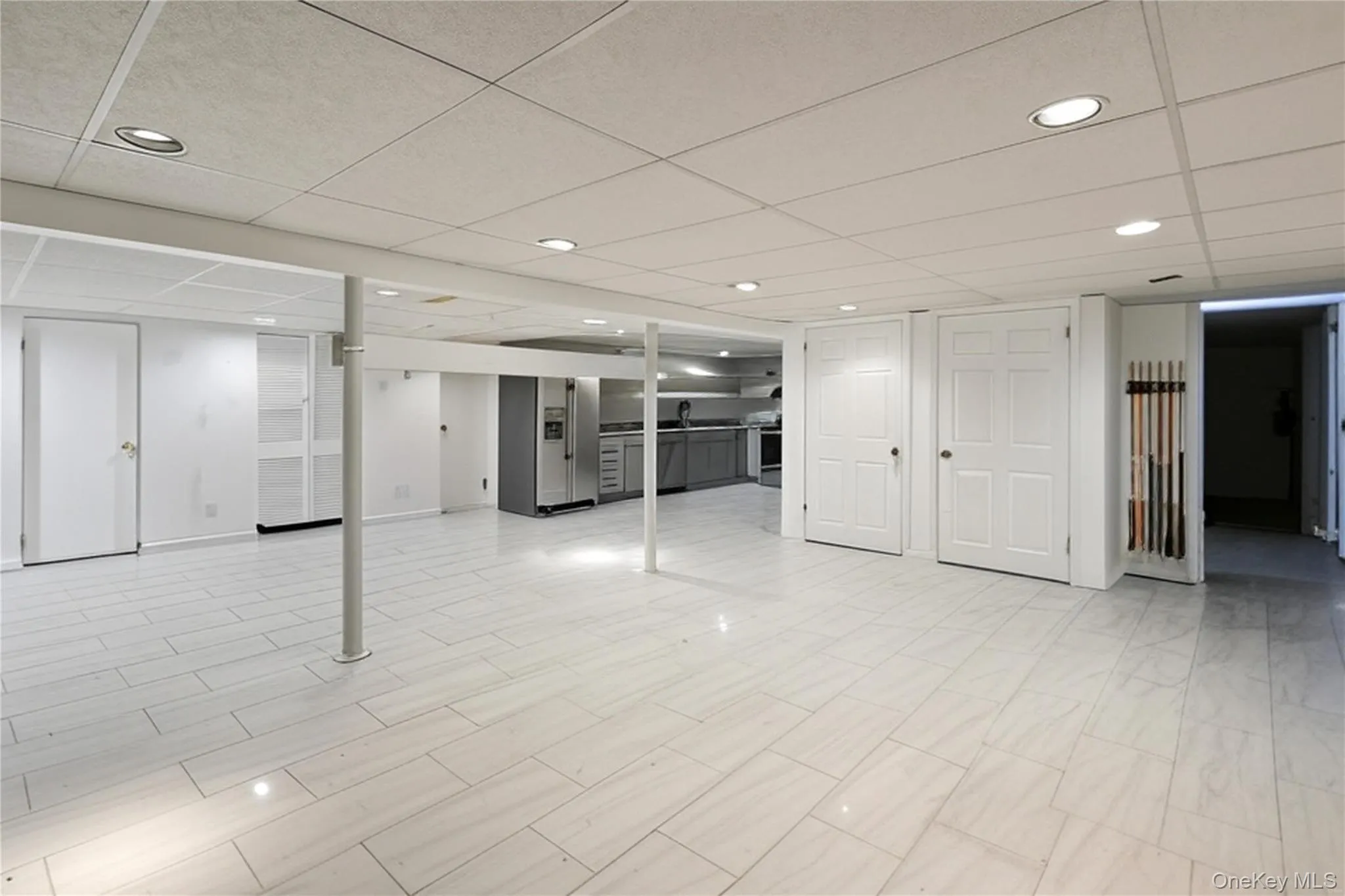 Finished basement featuring a drop ceiling, stainless steel refrigerator with ice dispenser, and recessed lighting Finished basement featuring a drop ceiling, stainless steel refrigerator with ice dispenser, and recessed lighting