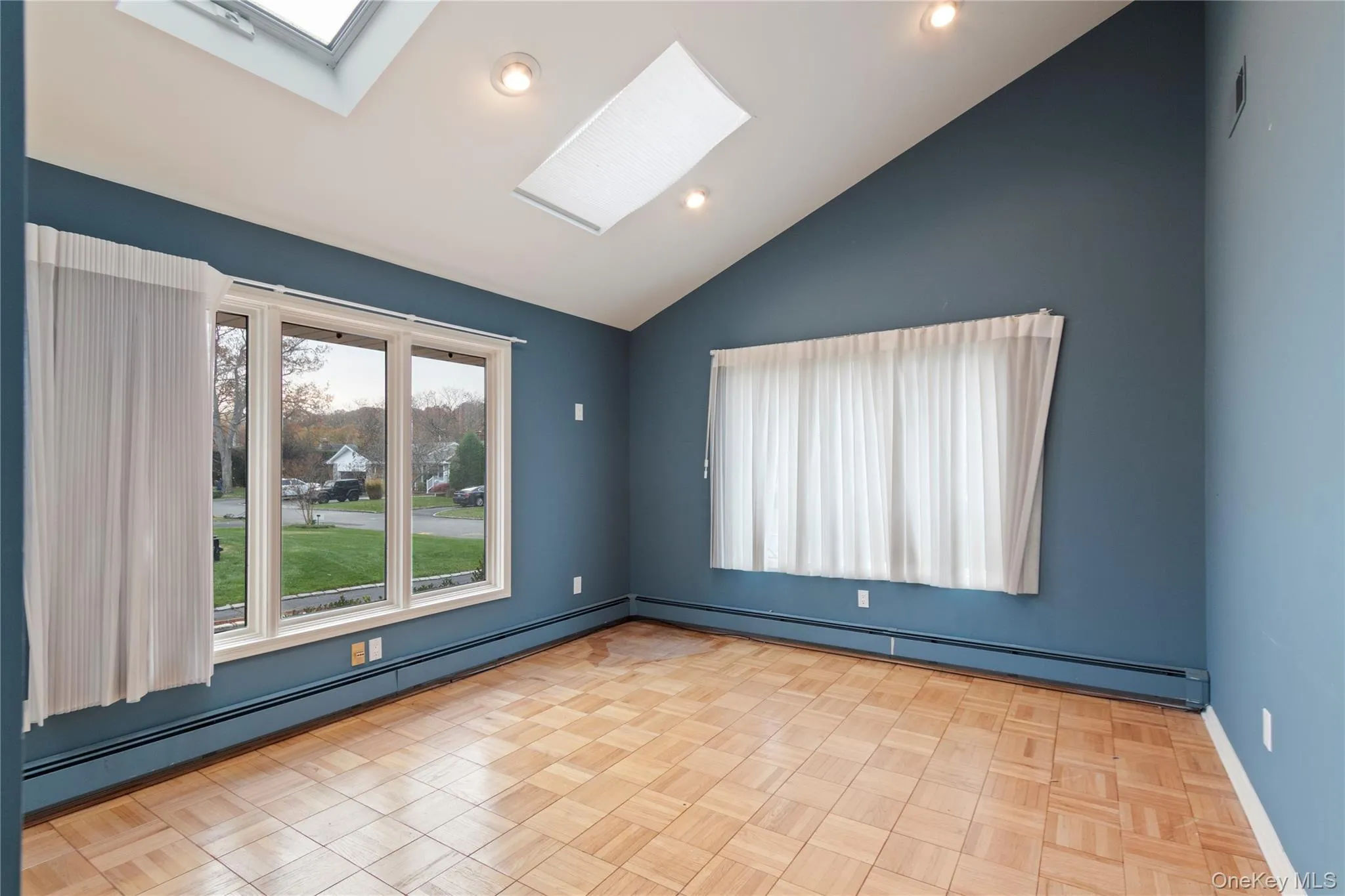 Empty room featuring baseboard heating, a skylight, vaulted ceiling, and recessed lighting Empty room featuring baseboard heating, a skylight, vaulted ceiling, and recessed lighting