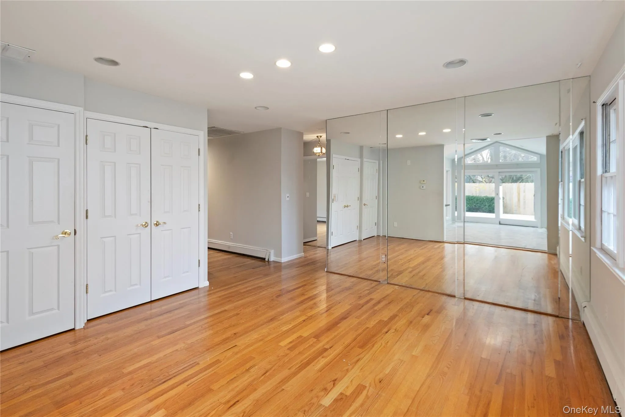 Unfurnished bedroom featuring a baseboard heating unit, light wood finished floors, multiple closets, and recessed lighting Unfurnished bedroom featuring a baseboard heating unit, light wood finished floors, multiple closets, and recessed lighting