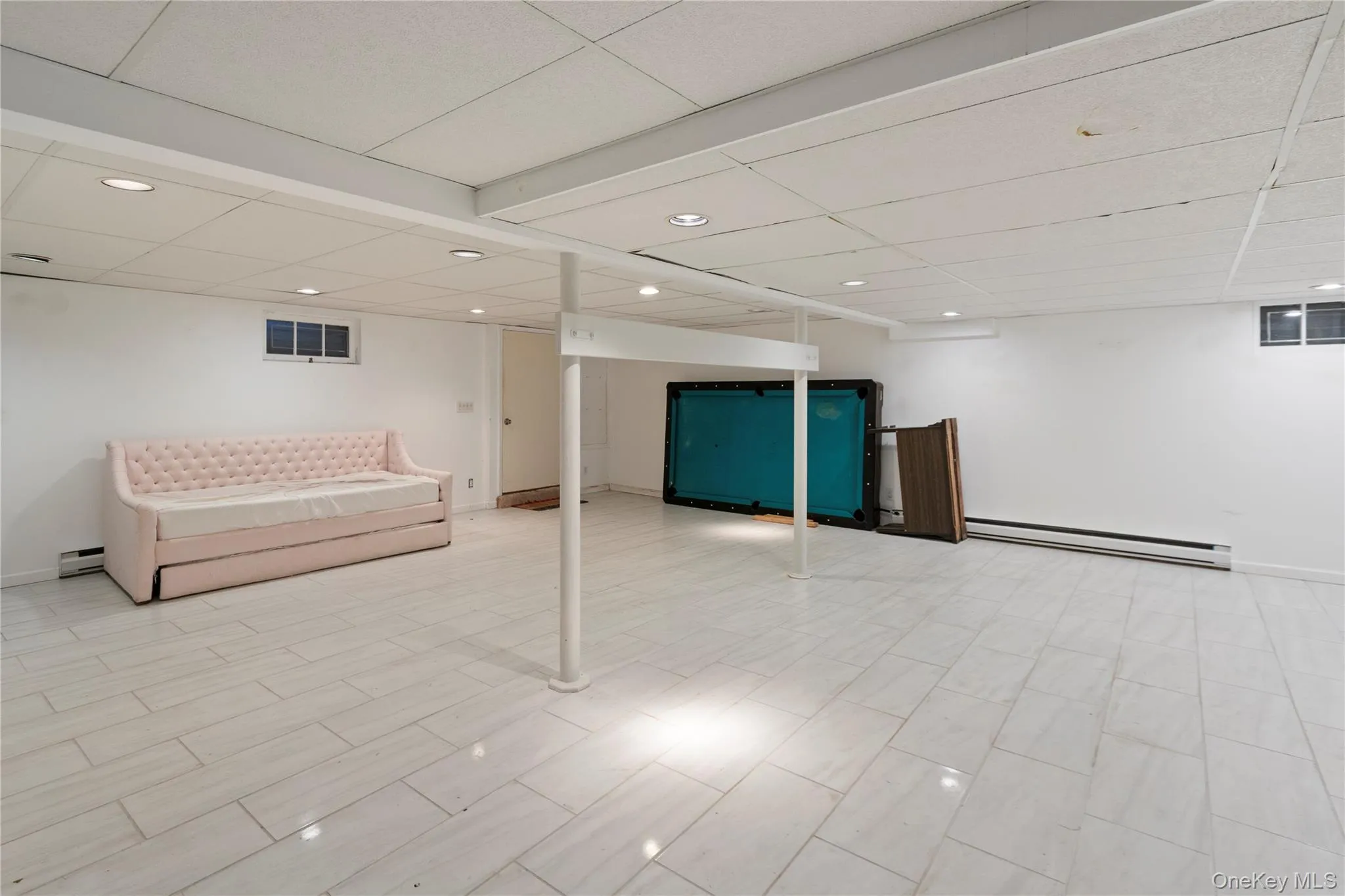 Finished basement featuring a drop ceiling, baseboard heating, recessed lighting, a baseboard radiator, and wood finish floors Finished basement featuring a drop ceiling, baseboard heating, recessed lighting, a baseboard radiator, and wood finish floors