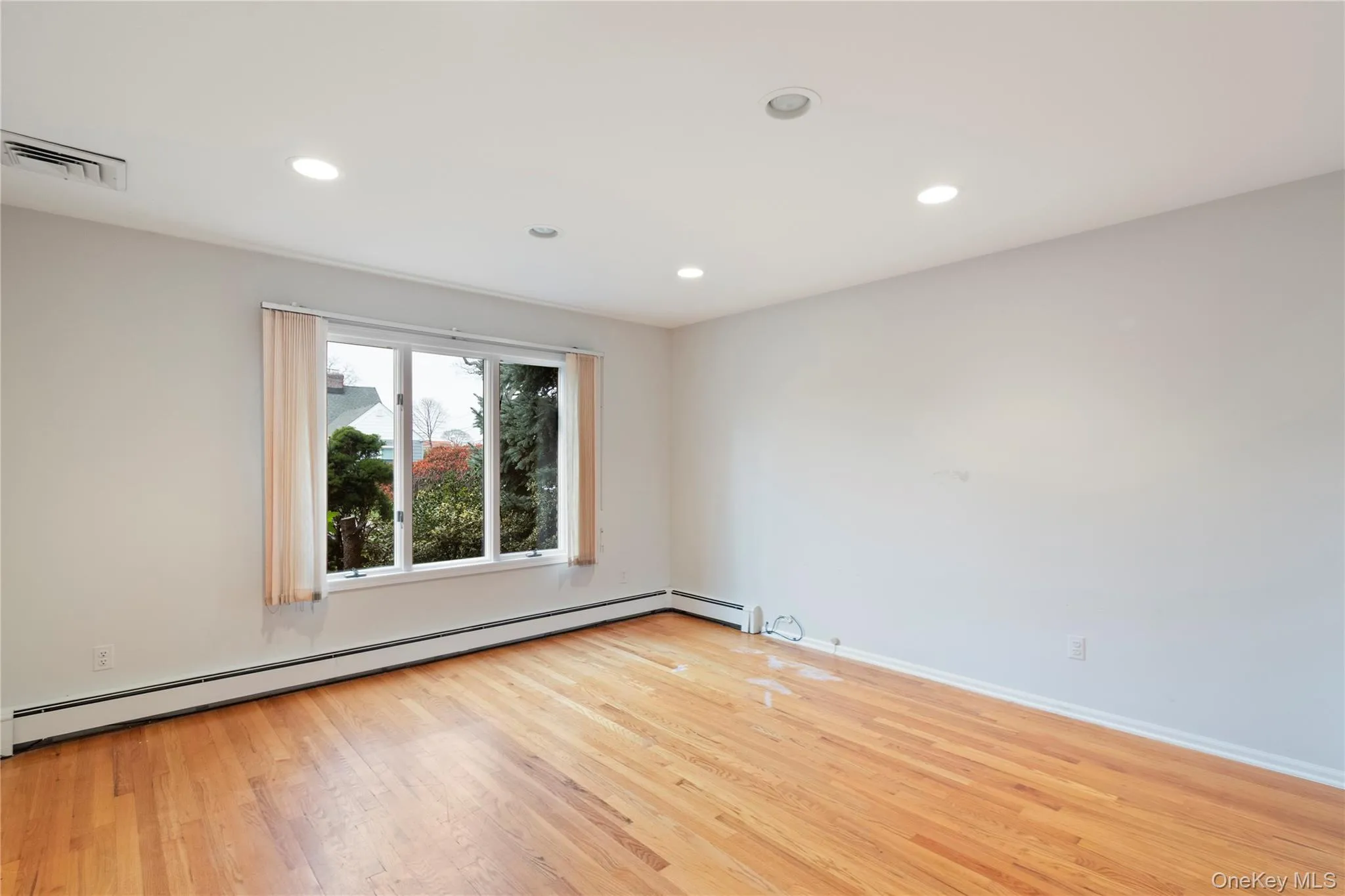 Empty room with light wood-style floors, a baseboard radiator, and recessed lighting Empty room with light wood-style floors, a baseboard radiator, and recessed lighting