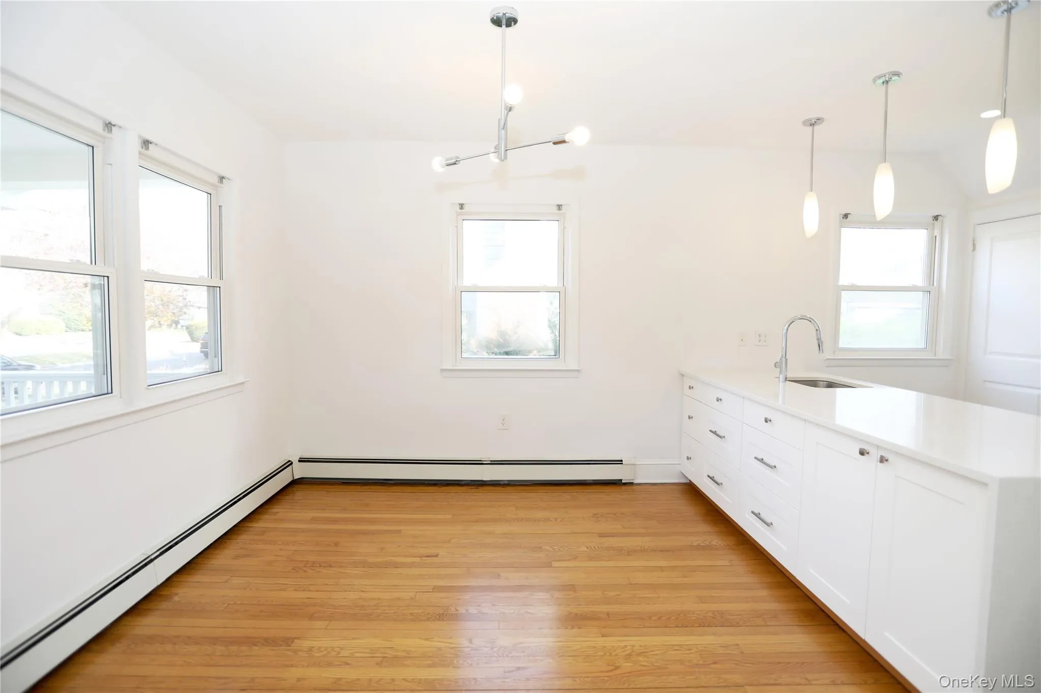 Kitchen featuring baseboard heating, a peninsula, light wood-style flooring, and pendant lighting Kitchen featuring baseboard heating, a peninsula, light wood-style flooring, and pendant lighting