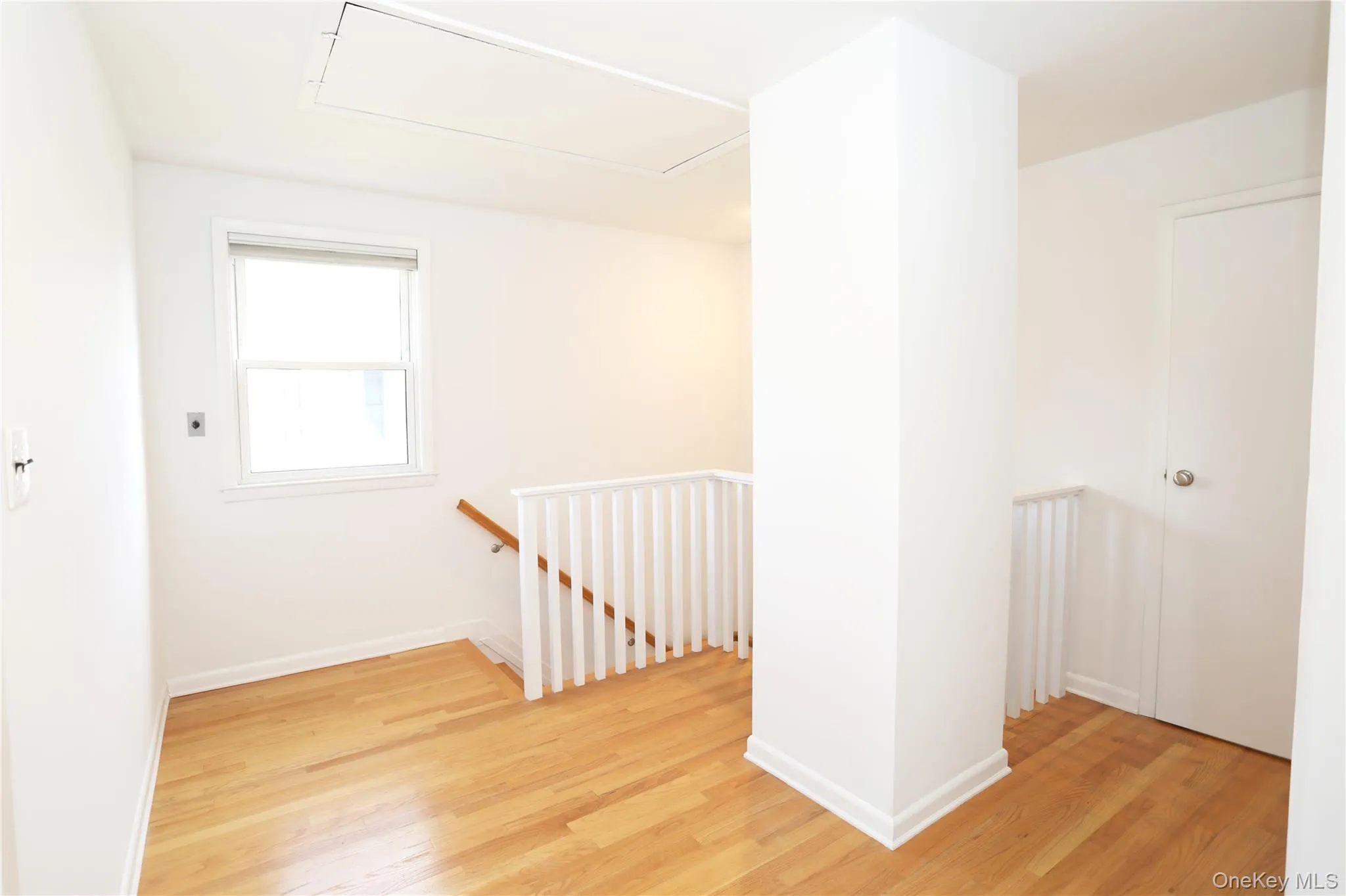 Hall featuring an upstairs landing, light wood-style flooring, and attic access Hall featuring an upstairs landing, light wood-style flooring, and attic access
