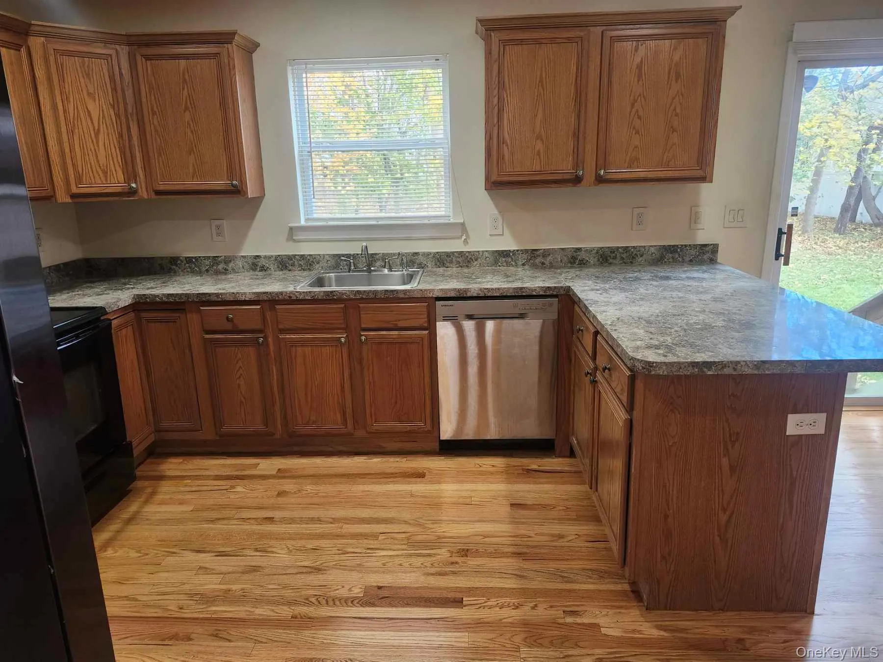 Kitchen featuring a peninsula, dishwasher, black range with electric stovetop, and light wood-style floors Kitchen featuring a peninsula, dishwasher, black range with electric stovetop, and light wood-style floors
