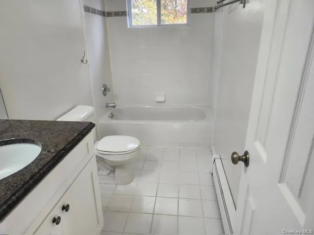 Full bath with vanity, baseboard heating, shower / washtub combination, and light tile patterned floors Full bath with vanity, baseboard heating, shower / washtub combination, and light tile patterned floors