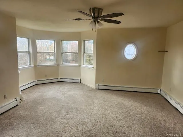 Primary Bedroom with light carpet, a baseboard heating unit, and ceiling fan Primary Bedroom with light carpet, a baseboard heating unit, and ceiling fan