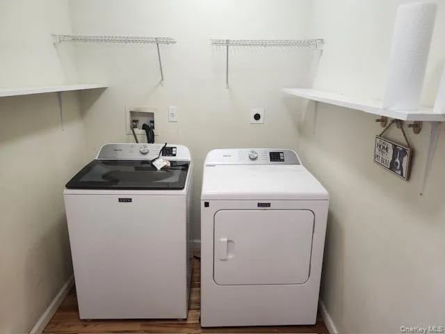 Washroom with washing machine and clothes dryer and wood finished floors Washroom with washing machine and clothes dryer and wood finished floors