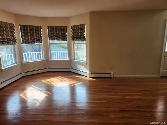 Spare room featuring dark wood finished floors and healthy amount of natural light Spare room featuring dark wood finished floors and healthy amount of natural light