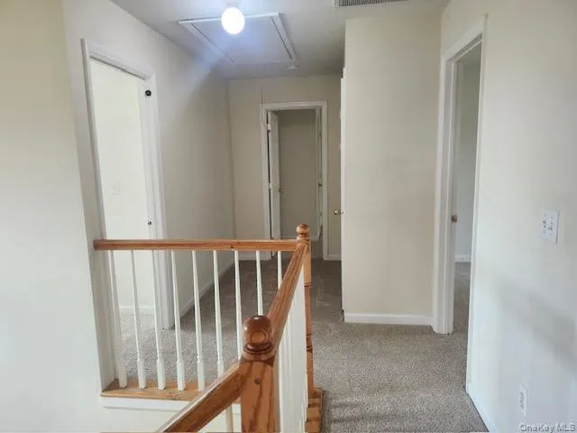 Hall featuring an upstairs landing, carpet floors, and attic access Hall featuring an upstairs landing, carpet floors, and attic access