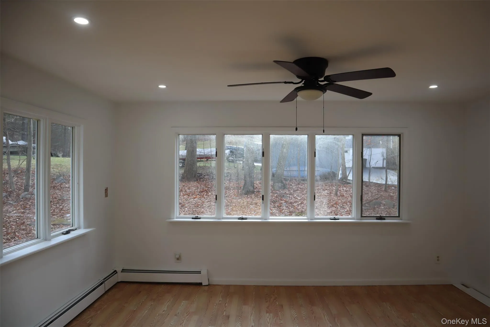 Unfurnished room with light wood-style floors, recessed lighting, baseboard heating, ceiling fan, and healthy amount of natural light Unfurnished room with light wood-style floors, recessed lighting, baseboard heating, ceiling fan, and healthy amount of natural light
